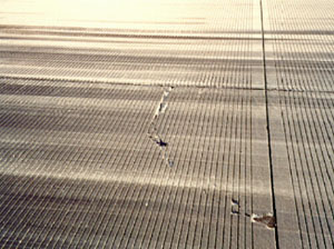 Overview photo of a PCC slab corner with a single corner break crack. The crack in the photo is noticeably spalled.