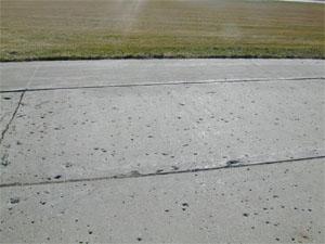 Overview photo of a PCC pavement with widespread popouts.  The popouts are visible in the photo as           'holes' in the surface where individual pieces of aggregate have come loose from the pavement's surface.