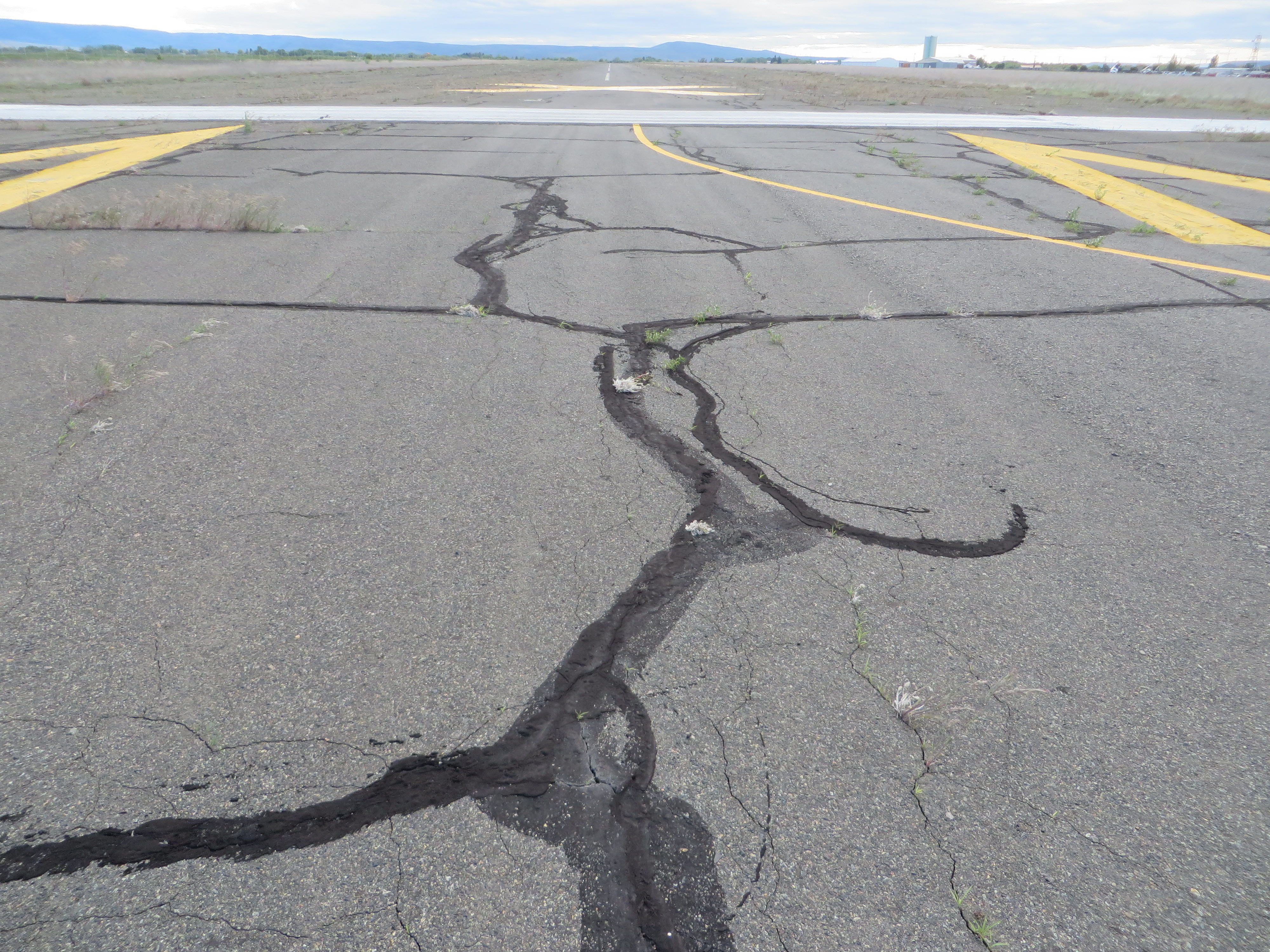 This picture shows an asphalt taxiway pavement with a good amount of block cracking.  The PCI of the pavement in the image is 60.